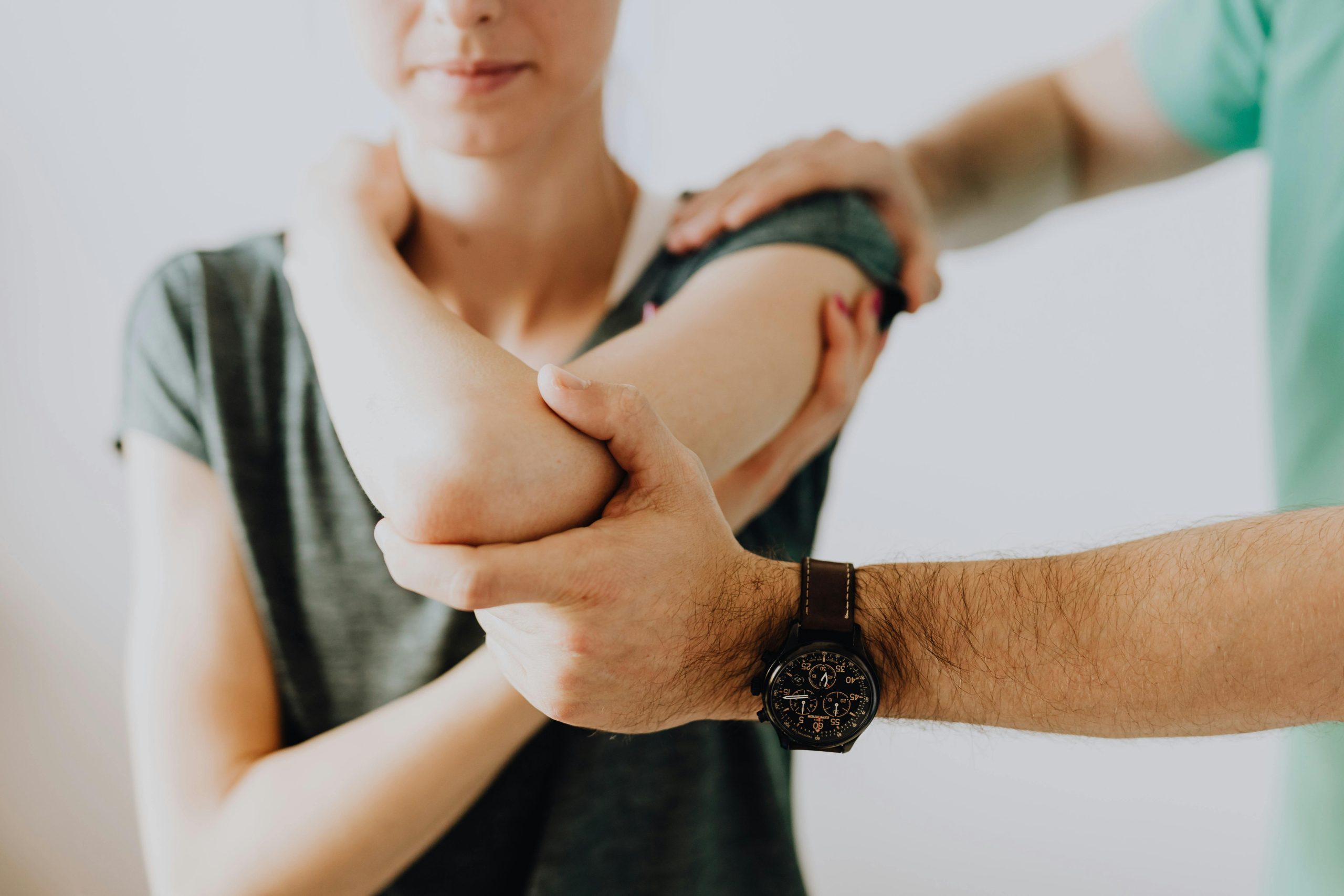 A physiotherapist assessing and stretching a woman's elbow at Moore Than Physio clinic in Glen Eden